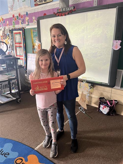 Kylea Wybiral, Grover Cleveland's February Stairclimber, poses with her plaque and a school staff member.